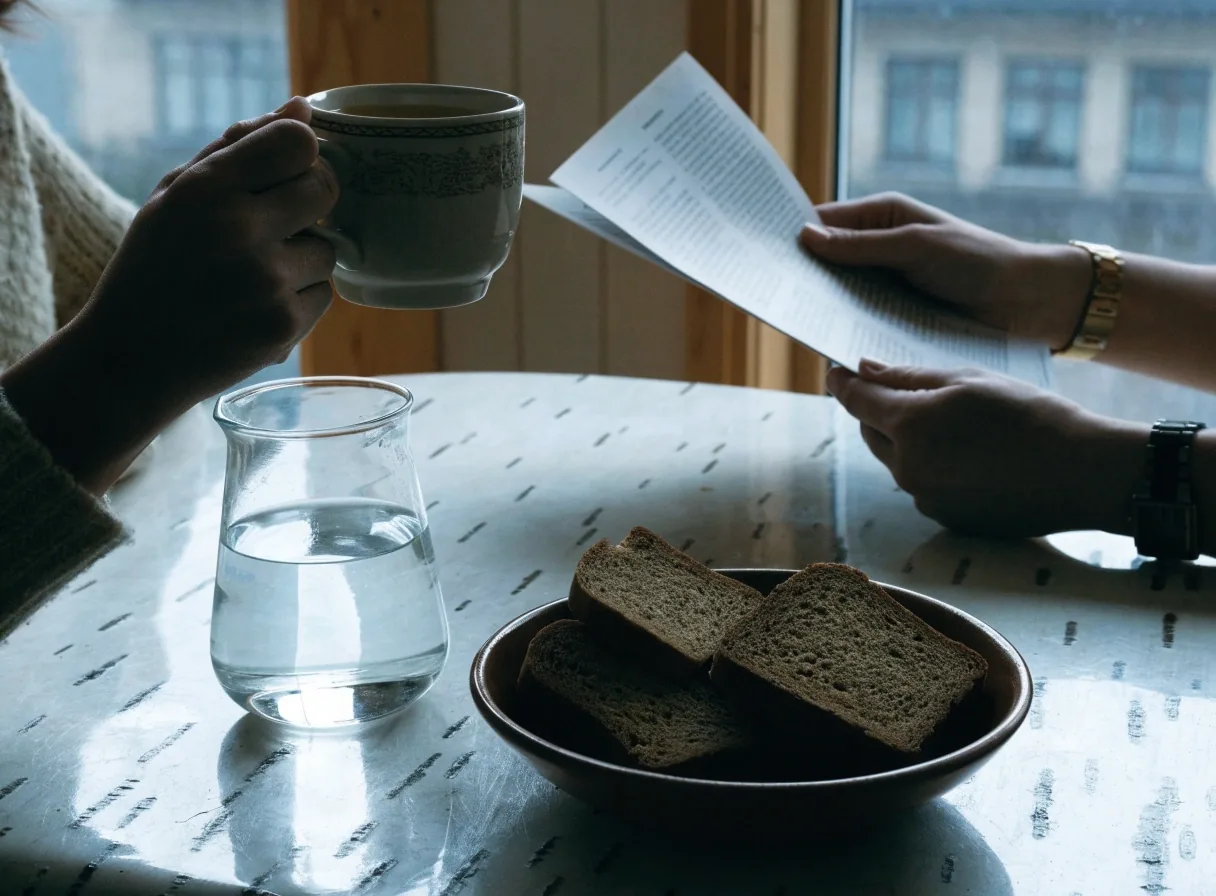 Two people reading and writing notes at a birch table in a Finnish apartment